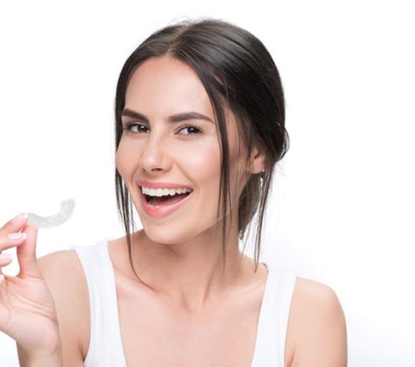 Happy young woman holding clear aligner