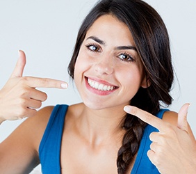 Woman pointing at her smile after cosmetic dentistry treatment