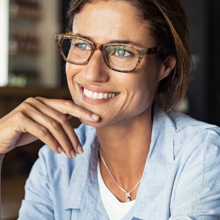 Smiling woman with glasses putting her hand under her chin