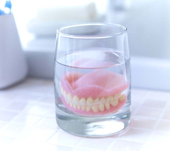Dentures soaking in glass of water