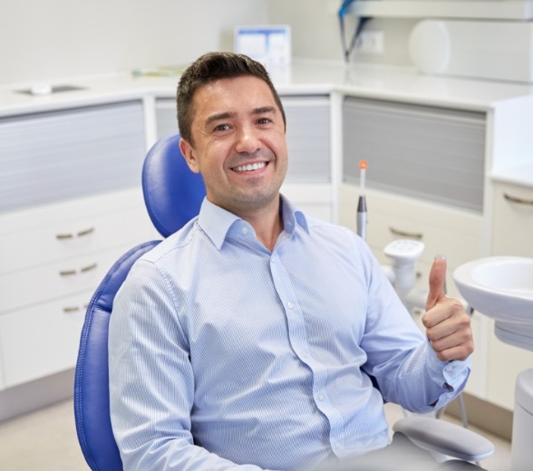 Man smiling and giving thumbs up in dental chair