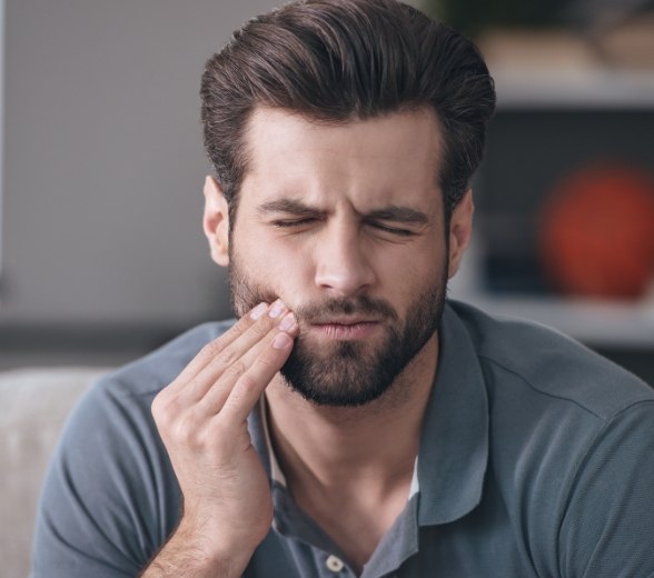 Man in need of tooth extractions holding his jaw in pain
