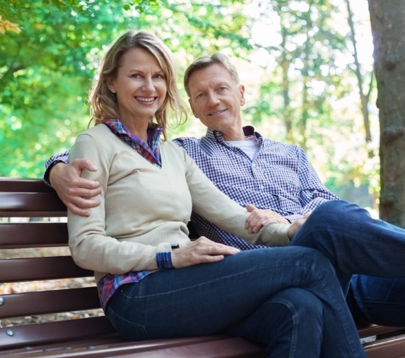 Man and woman smiling after replacing missing teeth with dental implants