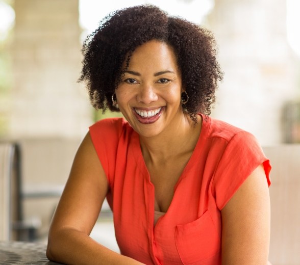 Woman smiling and wearing orange blouse