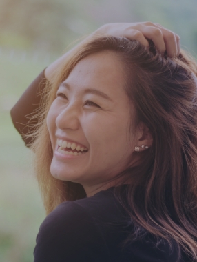 Woman with long dark hair smiling outdoors