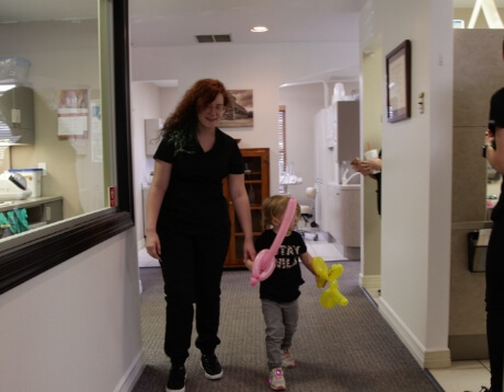 Dentla team member walking down hall with young dental patient