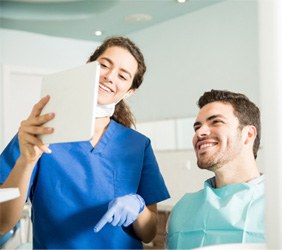 Patient and dentist smiling while looking at tablet in office