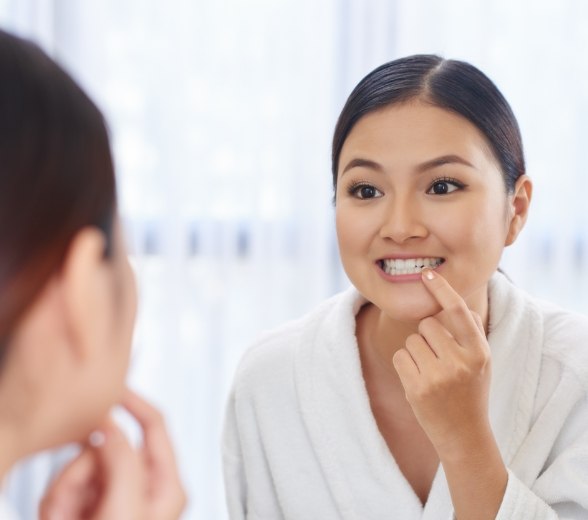 Woman looking at her gums in mirror