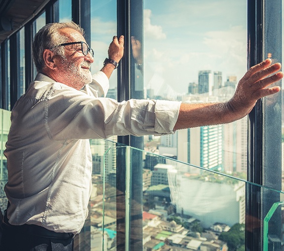 Man looking contentedly out of window at city skyline