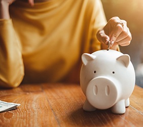 A person placing a coin in a piggy bank