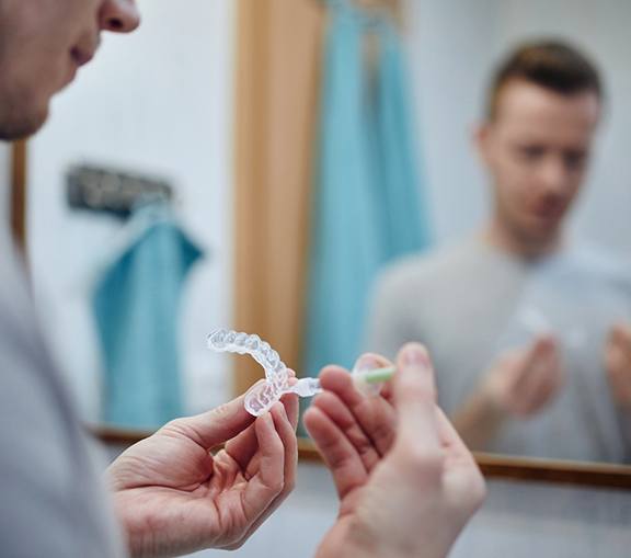 Man putting whitening gel in trays in his bathroom