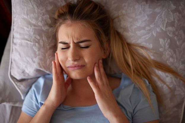 Woman experiencing jaw pain related to bruxism.