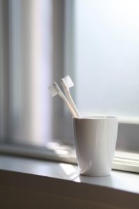 Two toothbrushes in a white cup