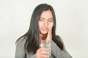 Woman with tooth sensitivity holding a glass of water