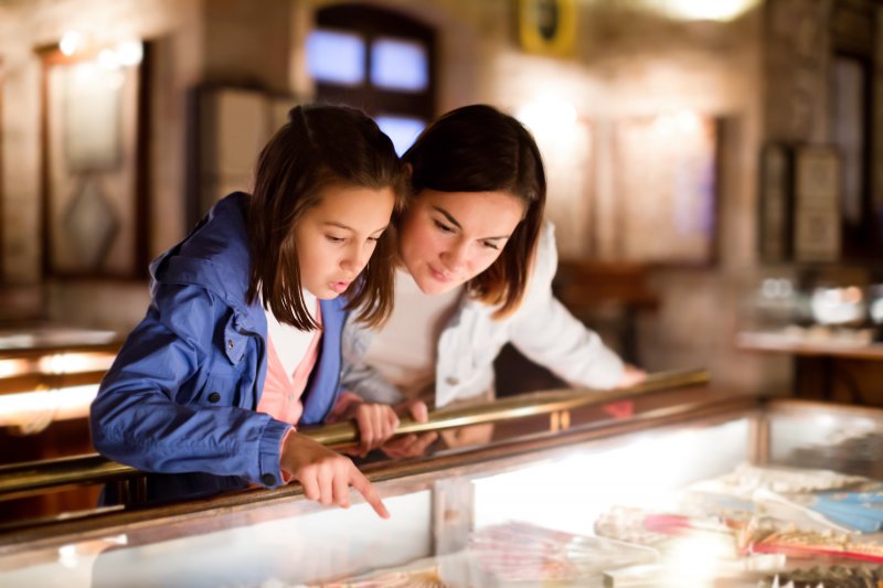 A mother and daughter looking at a museum display of ancient cosmetic dentistry