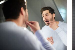 man looking into his mouth in a mirror